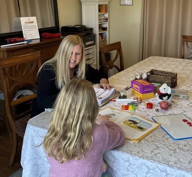 Sarah smiling as a young student reads a SIPPS story at her lesson table